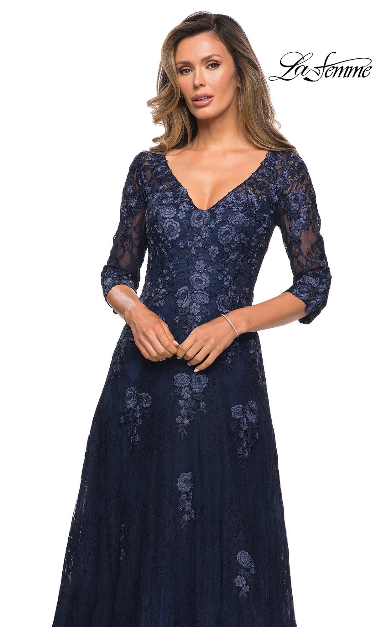 Woman wearing the Long Formal Dress: La Femme 28000 in navy with floral lace, three-quarter sleeves, and a V-neckline, posing against a white background.